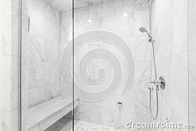 A shower with marble tiles and chrome showerhead. Stock Photo