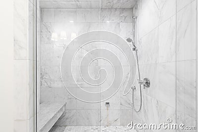 A shower with marble tiles and chrome showerhead. Stock Photo