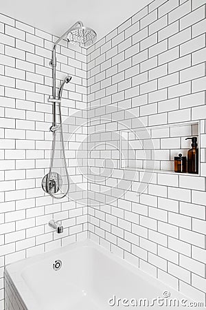 A shower with white subway tiles and chrome faucet. Stock Photo