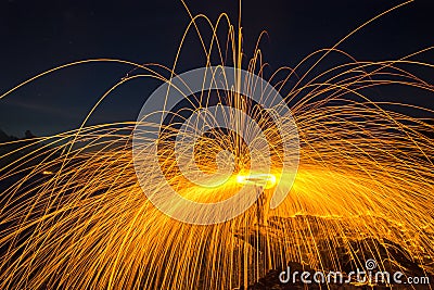 Showers of hot glowing sparks from spinning steel wool on the rock Stock Photo