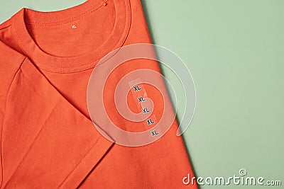 Showing size tag XL on orange t- shirt for selling in shop Stock Photo