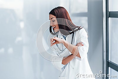 Showing to the side by finger. Young nurse indoors in modern clinic. Conception of healthcare Stock Photo