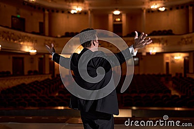 View from back on Middle Age Male entertainer, presenter or actor on stage. Arms to sides Stock Photo