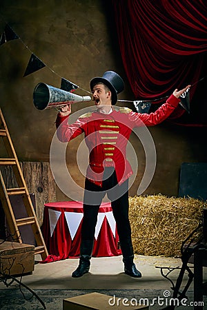 Vintage portrait of male retro circus entertainer expresses rejoice and announces start of show over dark retro circus Stock Photo