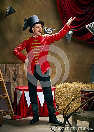 Vintage portrait of male retro circus entertainer expresses rejoice and announces start of show over dark retro circus Stock Photo