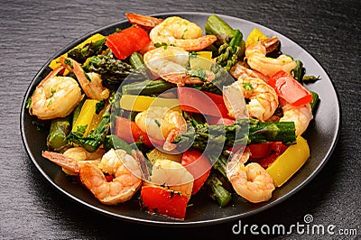 Shrimps prepared with asparagus, tomatoes and paprika. Stock Photo