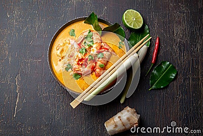 Shrimps Tom Yam Kung in grey bowl with thai spices on autentic tray top view, wooden background Stock Photo