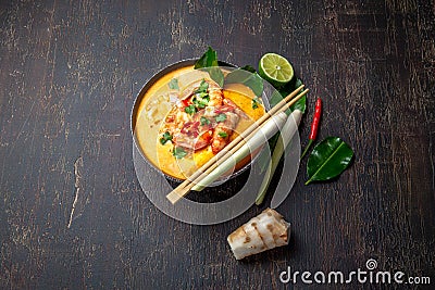 Shrimps Tom Yam Kung in grey bowl with thai spices on autentic tray top view, wooden background Stock Photo