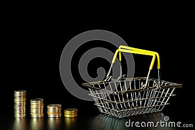 Shrinking stacks of coins and an empty grocery basket Stock Photo