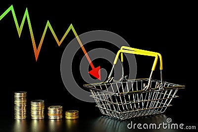 Shrinking stacks of coins and an empty grocery basket on a black background, an arrow showing the economy falling Stock Photo