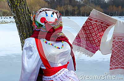 Shrovetide doll in colorful headscarf and sarafan near tree Stock Photo