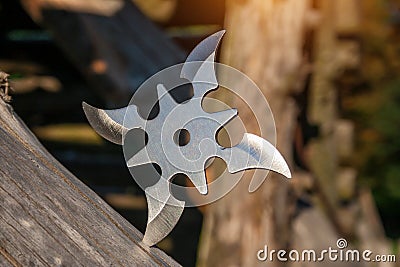 Shuriken throwing star, traditional japanese ninja cold weapon stuck in wooden background Stock Photo