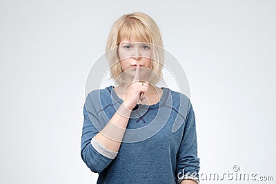 Serious lovely female asks to keep secret information confidential, dressed in blue pulover Stock Photo