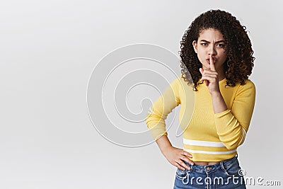 Shut up listen carefully. Serious-looking young mixed-race woman curly hairstyle demanding quiet shushing show shhh Stock Photo