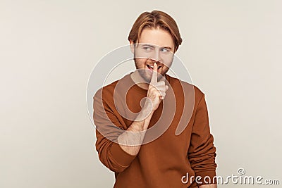 Shut up, stay quiet! Portrait of positive man wearing sweatshirt showing silence gesture with finger on lips Stock Photo