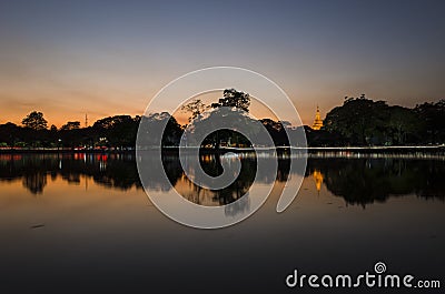 Shwedagon golden Pagoda reflecting in Kandawgyi Lake at dusk in Bogyoke Park. Yangon Stock Photo