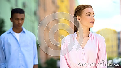 Shy multiracial boyfriend looking at beautiful girl from behind, chasing beloved Stock Photo