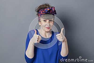 Shy retro 30s woman smiling with two thumbs up Stock Photo