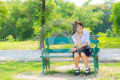 Shy Thai schoolgirl sitting on a bench Stock Photo