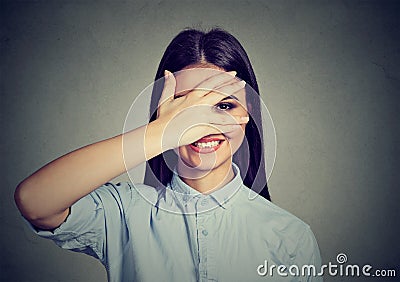 Shy woman hiding face laughing timid. Cute girl smiling through hand. Stock Photo