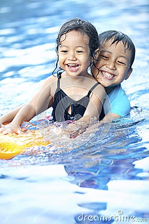 Sibling having fun at swimming pool Stock Photo