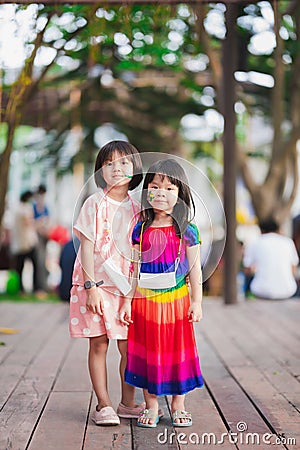 Sibling stand to take pictures together. Sisters paint cartoons on their faces on Easter. Children have fun in outdoor playground Stock Photo