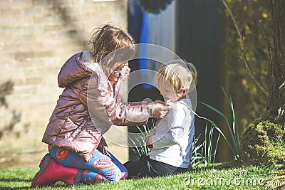 Siblings playing together a boy and girl are playing outside in a garden during daytime Stock Photo