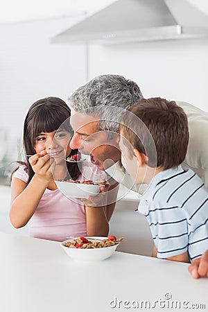Siblings sharing cereal with their father Stock Photo