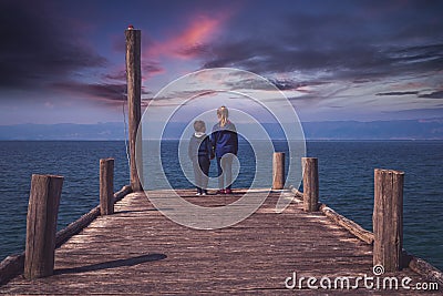 Siblings standing on a wooden pier Stock Photo