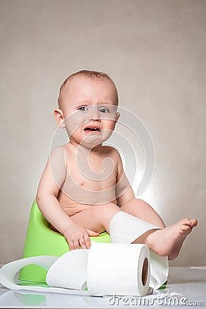 Sick baby constipation, colic, bloating, indigestion heartburn, digestion, pain, diarrhea. sitting on the potty with toilet paper Stock Photo