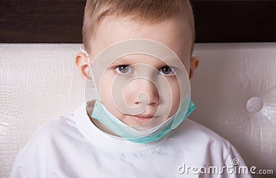 Sick boy sitting in bed in medical mask and doesn t feel well Stock Photo
