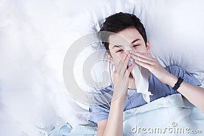 Sick boy, teenager caught a cold, lying in bed, high temperature, bed rest, headache, poor health Stock Photo