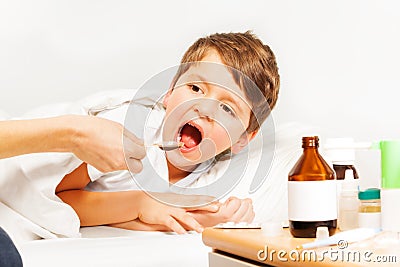 Sick Caucasian kid boy taking meds laying in bed Stock Photo