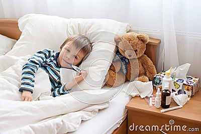 Sick child boy lying in bed with a fever, resting Stock Photo