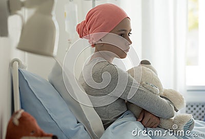 Sick child with cancer sitting in hospital bed Stock Photo