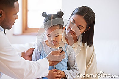 Sick child at doctors office with her mother. Little girl sitting with mother while male paediatrician listen to chest Stock Photo