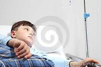 Sick child isolated in hospital room with absent minded looking over lying down on bed wearing a pajama Stock Photo