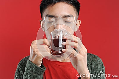 Sick cold and headache Young Asian man wearing a sweater while drinking hot tea Stock Photo