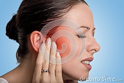 Sick female having ear pain touching her painful head Stock Photo