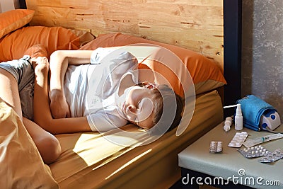Sick girl in bed. A little girl in pain. The child is drinking a lot of medicine. Stock Photo