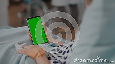 Sick girl holding mock up green screen chroma key phone with isolated display during recovery Stock Photo