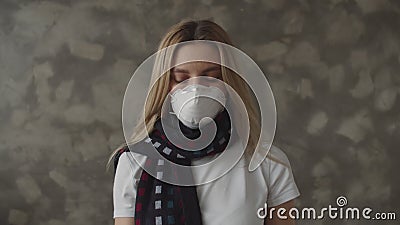 A sick girl in a medical mask with a scarf around her neck raises the thermometer, looks at the temperature and sighs. Heavily. A young woman infected with the stock footage A sick girl in a medical mask with a scarf around her neck raises the thermometer, looks at the temperature and sighs. Heavily. A young woman infected with the stock footage