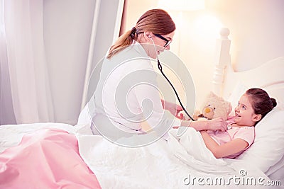 Dark-haired general practitioner sitting near cute little girl feeling sick Stock Photo