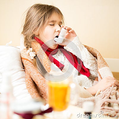 Sick girl with respiratory illness lying in bed and using inhale Stock Photo