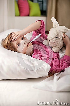 Sick girl resting in bed with fever meassuring temperature with Stock Photo