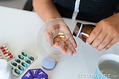 Sick illness woman hold two pill on hand pouring capsules from medication bottle take painkiller supplement medicine Stock Photo