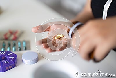 Sick illness woman hold two pill on hand pouring capsules from medication bottle take painkiller supplement medicine Stock Photo