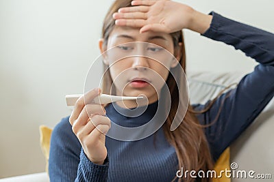 Sick, influenza asian young woman, girl headache have a fever, flu and check thermometer measure body temperature, feel illness Stock Photo
