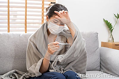 Sick, influenza asian young woman, girl wearing face mask in headache have a fever, flu and check thermometer measure body Stock Photo