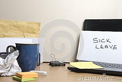 Sick leave message left on a messy office desk Stock Photo